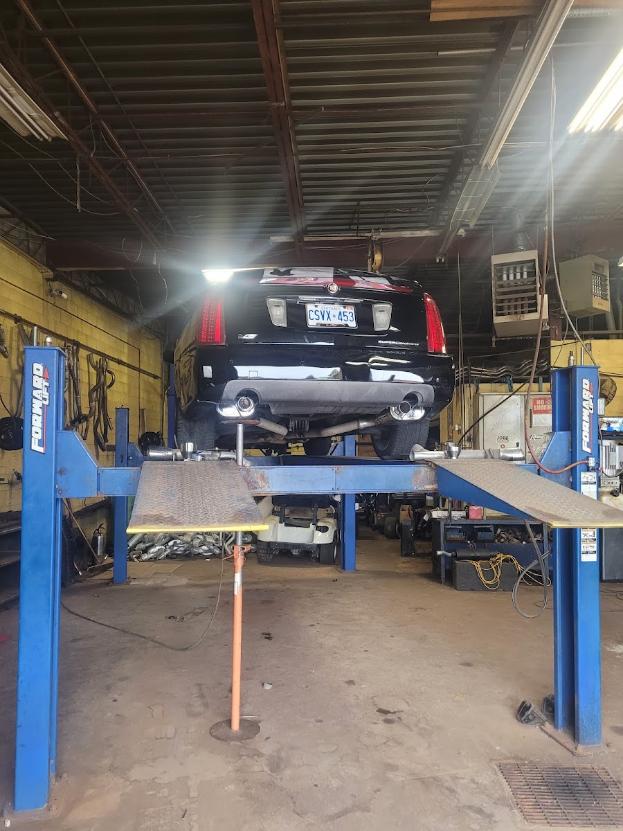 A black Cadillac on the four-post lift inside C and D Masters with a custom exhaust system installed